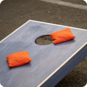 Cornhole board with orange bean bags